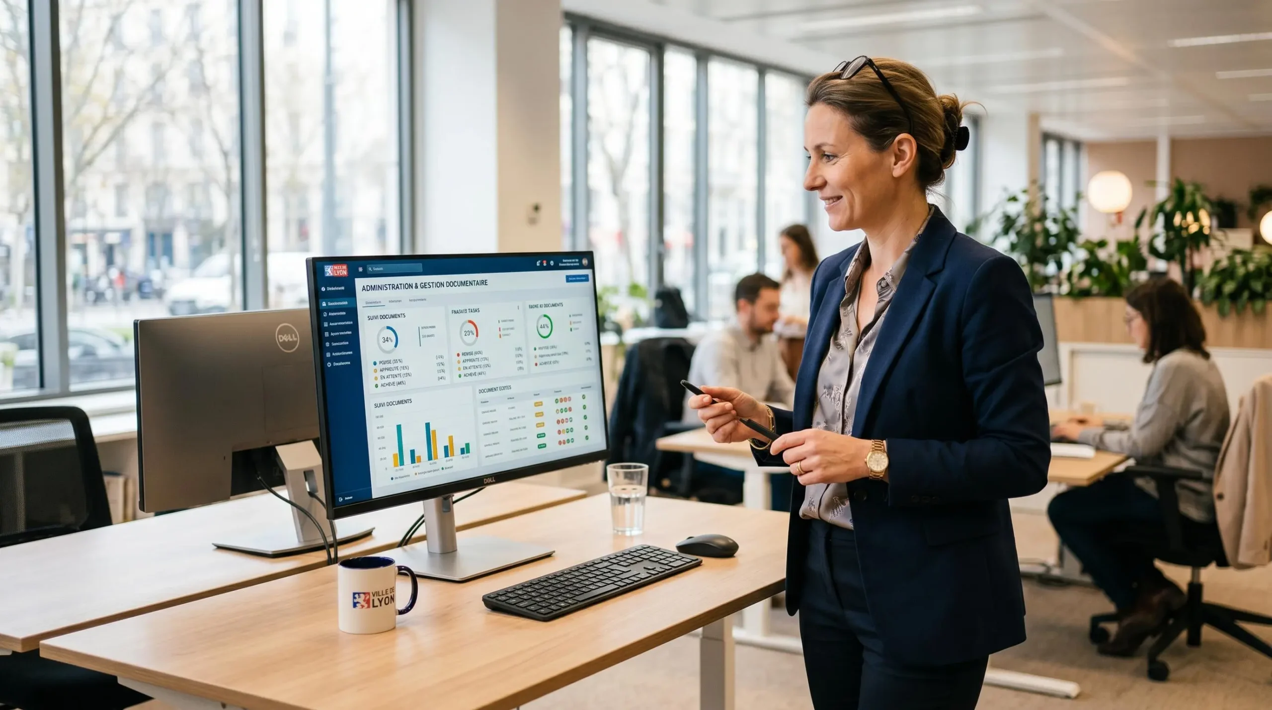 Responsable administratif consultant une interface de suivi d'envois dématérialisés dans un open space moderne